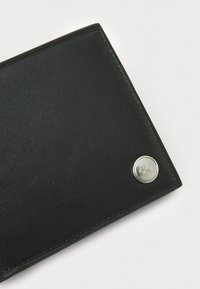 Portefeuille en cuir noir avec une texture lisse, doté d'un accent en matériel logo argenté et de coutures précises le long des bords.
