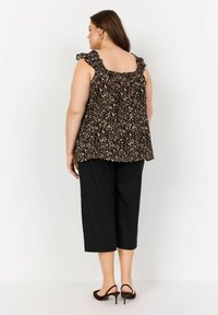 Svart ärmlös top med ett leopardmönster, volangband och en lös passform, ihopparad med svarta cropped byxor och klacksandaler.