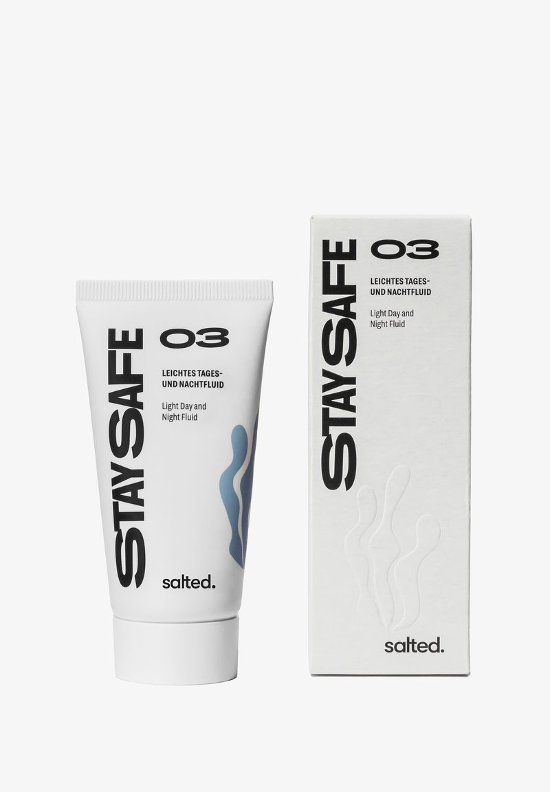 Weißer Behälter und Box mit "Stay Safe" Licht Tages- und Nachtfluid. Der Behälter hat schwarzen Text und ein blaues wavy Design. Minimalistisches Verpackungsdesign.