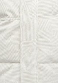 Tecido exterior branco acolchoado com padrão geométrico sutil e textura em relevo; apresenta costura vertical e acabamento suave.