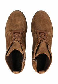 Bottines en daim marron avec un bout arrondi, un laçage sur le devant et des zips sur les côtés. Texture douce, hauteur cheville avec une semelle plate en caoutchouc.