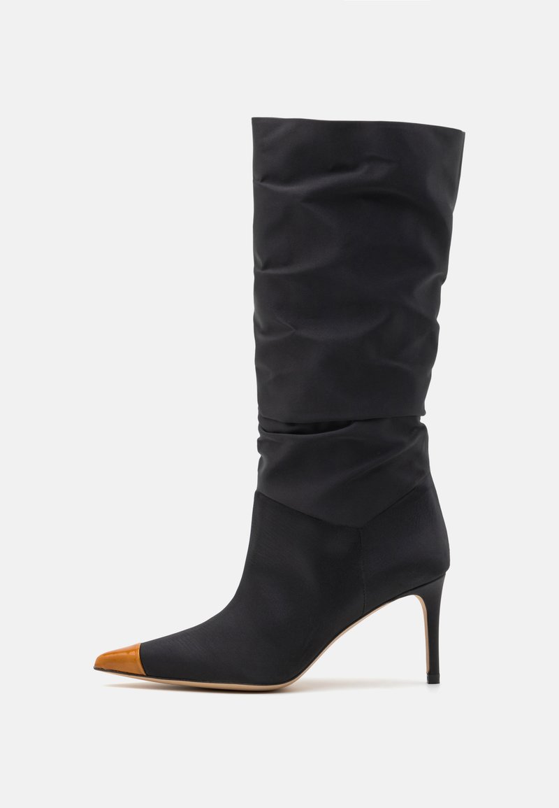 Black satin high-heeled boot with slouchy upper, pointed toe, and contrasting tan leather tip. Features a slender stiletto heel.