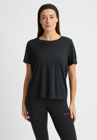 Czarna koszulka sportowa z krótkim rękawem, okrągłym dekoltem i luźnym krojem. Wykonana z gładkiego, lekkiego materiału. Bez widocznych wzorów ani akcentów.