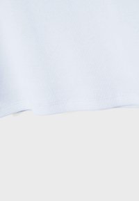 Nærbillede af lyst blå ribbet stof med en syet kant mod en ensfarvet baggrund.