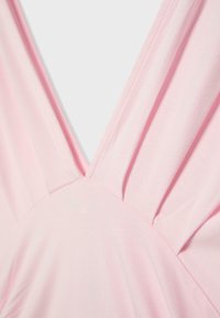 Jasnoróżowa tkanina z dekoltem w kształcie litery V i marszczeniem na miękkiej, gładkiej fakturze, prawdopodobnie część ubrania.