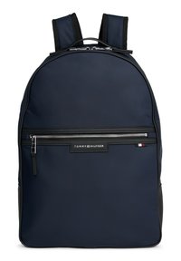 Zaino navy realizzato in tessuto resistente con una finitura liscia, dotato di una tasca anteriore con zip, patch con logo e spallacci imbottiti.