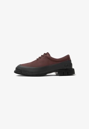 Maroon lace-up shoes with a thick black rubber sole featuring a ridged design. Side profile shows smooth upper texture and sturdy construction.
