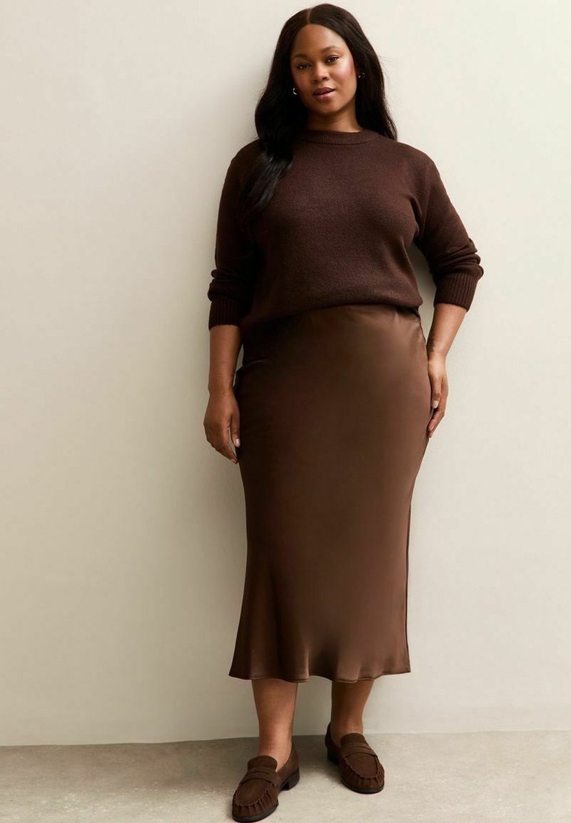 Brown gebreide trui, satijnen bruine midi-rok en bruine loafers. Soepele textuur met een getailleerd silhouet en subtiele glans.