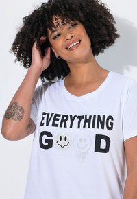 Bílé bavlněné tričko s výrazným černým nápisem "EVERYTHING GOOD" doplněným o grafiky smajlíka a ducha. Krátké rukávy a kulatý výstřih.