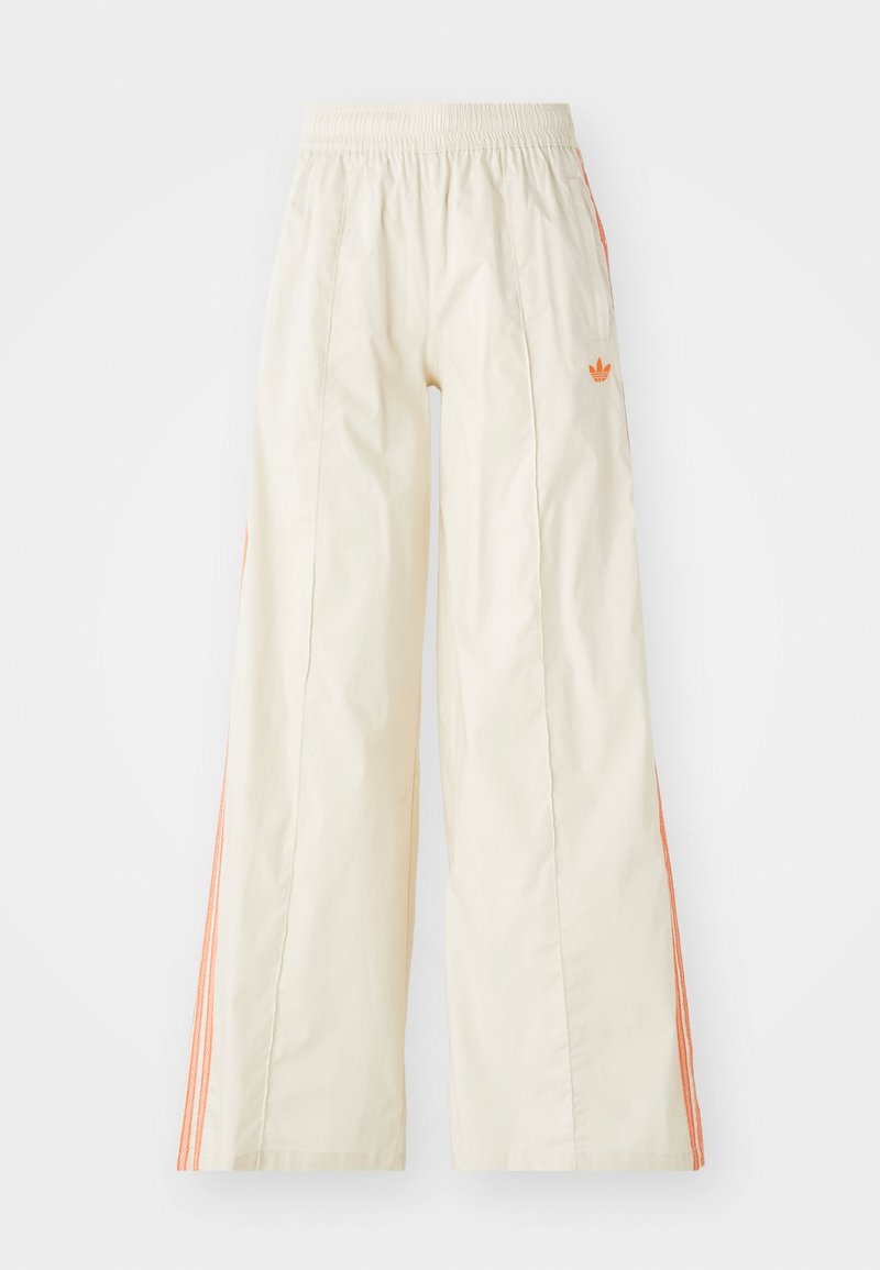 Kremowe spodnie o szerokich nogawkach z elastycznym paskiem w talii, z pomarańczowymi paskami po bokach i małym pomarańczowym logo z przodu.