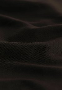 Tejido negro texturizado con un patrón acanalado, que muestra pliegues profundos y una superficie suave, adecuado para diversas aplicaciones textiles.