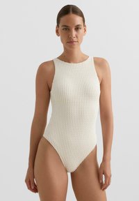 Biely textúrovaný plavky s vysokým v�ýstrihom a bez rukávov. Má priliehavý strih a jemný vzorovaný detail.