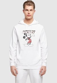 Fehér kapucnis pulóver, elöl Mickey Mouse grafikai mintával, piros pöttyös rövidnadrág dizájnnal. Kanguru zsebe és húzózsinóros kapucnija van.