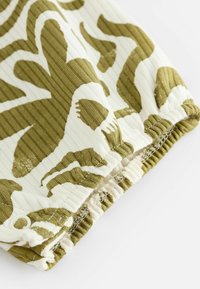 Tissu en coton présentant un motif abstrait vert et blanc, avec un design côtelé texturé et un ourlet élastiqué pour un ajustement parfait.