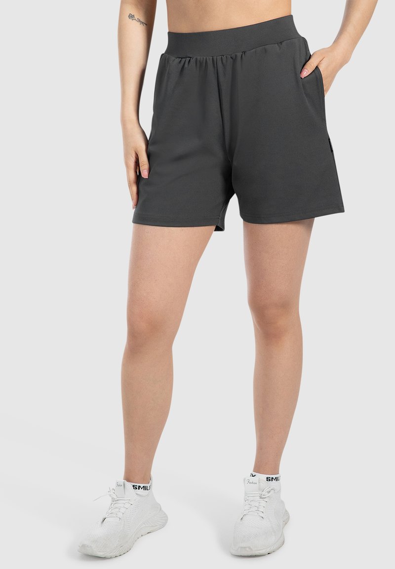 Donkergrijze sportshorts met een elastische tailleband, zijzakken en een gladde, lichte stof. Gekocht met witte sneakers.