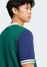 Green and blue short-sleeve polo shirt with a textured finish, featuring a white collar and striped accents on the sleeves.