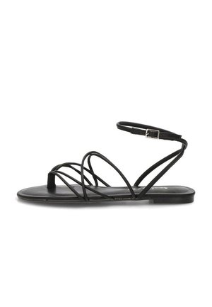 Sandalia plana negra con finas correas cruzadas, lazo para el dedo y correa ajustable en el tobillo con hebilla plateada.