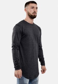 Langsleeve donkergrijze shirt met een ronde halslijn en een afgeronde zoom. De stof lijkt zacht met een gladde textuur. Draag met denim jeans.