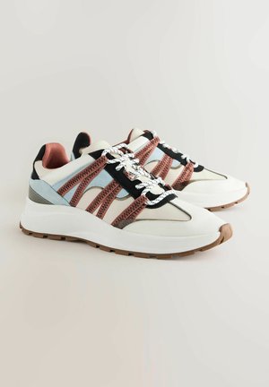 Zapatillas blancas con acentos de malla en rosa y negro, talón gris, punta redonda y suela blanca texturizada. Presenta cordones en contraste y patrones de costura.