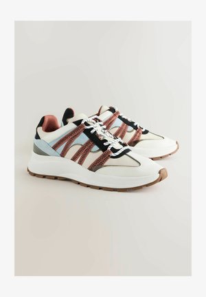 Witte sneakers met roze en zwarte mesh accenten, grijze hak, ronde neus en textuur witte zool. Heeft contrasterende veters en gestikte patronen.