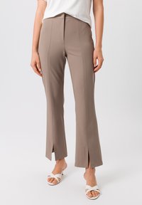 Bordeaux, op maat gemaakte broek met een flared snit en voorknopen. Gemaakt van een soepele stof, met zichtbare stiksels langs de naden.