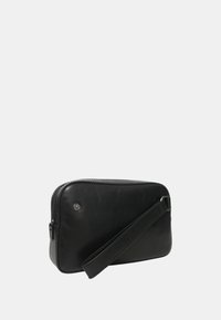 Borsa nera in pelle con forma rettangolare, chiusura con zip e manico per il polso. Texture liscia con design minimalista e un piccolo accento argentato.