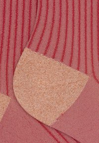 Tessuto a costine in tonalità rosa con dettaglio a toppa metallica dorata a contrasto sulla punta. Tessitura liscia con una leggera brillantezza.