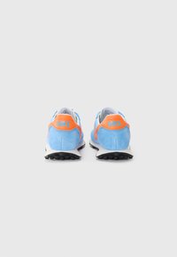 Sneaker in suede blu con dettagli arancioni, dotati di una suola intermedia bianca e suola esterna in gomma nera. La vista da dietro mostra il logo e i dettagli del design.