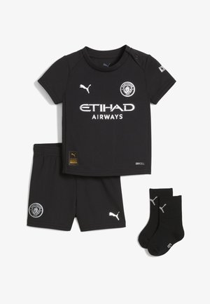 Echipament sport pentru copii de culoare neagră, compus dintr-o cămașă cu mânecă scurtă, pantaloni scurți și șosete. Fabricat dintr-un material care absoarbe umezeala, cu logo-uri și accente albe.