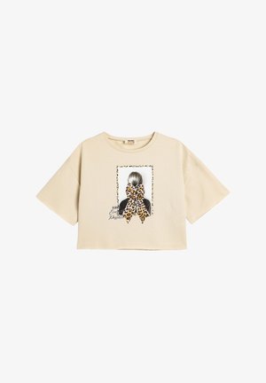 Beige cropped t-shirt van katoen, met een grafische print van een meisjeskapsel met een luipaardenkleurige strik en tekstaccenten.