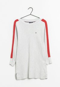 Suéter gris de manga larga con textura acanalada, con franjas rojas en los hombros, aberturas laterales y un pequeño logo en la parte delantera. Colgado de un gancho negro.