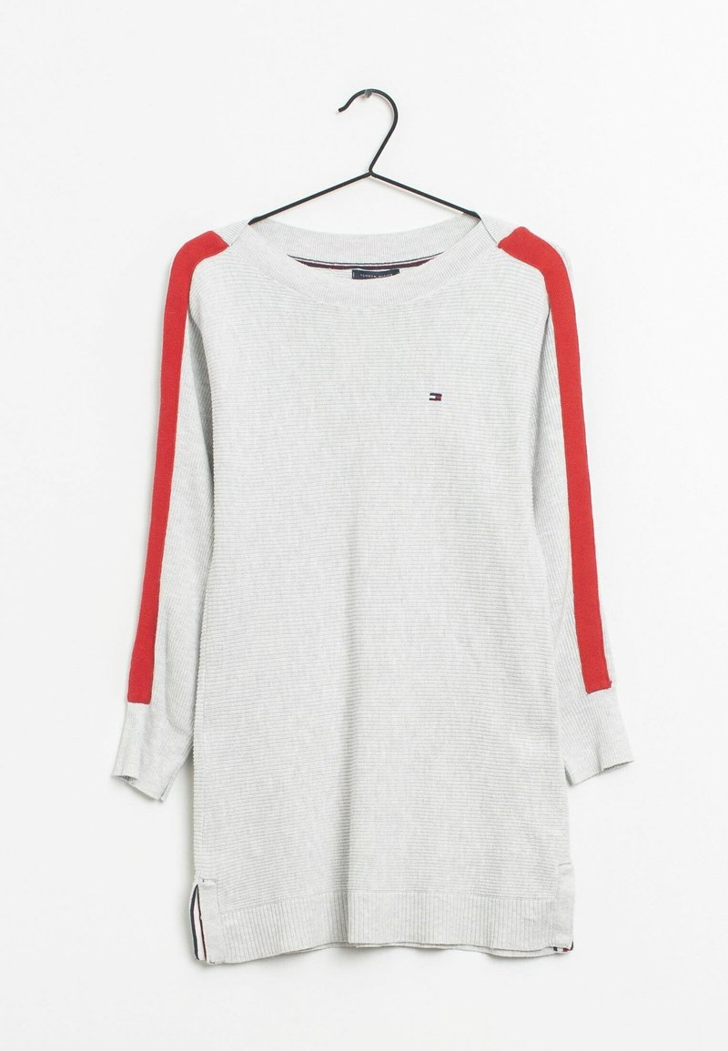 Suéter gris de manga larga con textura acanalada, con franjas rojas en los hombros, aberturas laterales y un pequeño logo en la parte delantera. Colgado de un gancho negro.