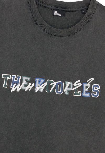 Tamsiai pilkas medvilninis marškinėliai su užrašu "THE KOOPLES" ir "WHAT O" įvairiomis spalvomis, skirtingais šriftų stiliais ir tekstūromis.