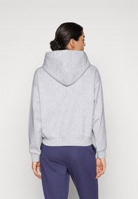 Felpa grigia con un ampio cappuccio a punta, polsini e orlo a coste, e una vestibilità morbida. Tessuto dalla texture morbida, design minimalista, senza loghi visibili.