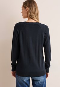 Pull noir en tricot avec des manches longues, des poignets et un ourlet côtelés, et des coutures d'épaule raglan. Design uni, sans motifs ni accents visibles.