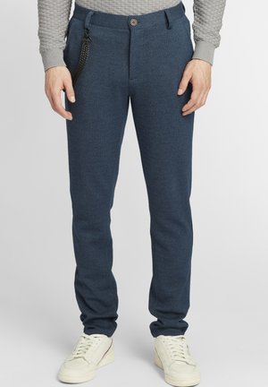 Námornícke modré tkané nohavice so slim fit strihom, elastickým pásom a gombíkovým zapínaním. V kombinácii s krémovými teniskami. Textúrovaná látka s jemným vzorom.