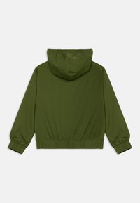 Zelená bunda s kapucňou, vyrobená z hladkého materiálu. Má elastické manžety a zberaný spodný lem pre priliehavý vzhľad, jednoduchý dizajn bez vzorov.