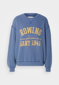 Sweat-shirt bleu avec un texte jaune "ROWING GANT 1949" et un graphique d'un rameur dans un bateau sur la poitrine.