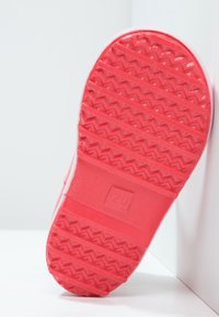 Rode rubberen schoenzool met een textured zigzagpatroon, voorzien van een rechthoekig gedeelte met het label "20" en groeven voor grip.