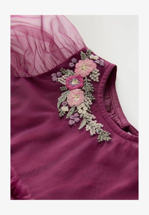 Haut en tissu bourgogne avec broderie florale dans des tons de rose, de vert et de violet, agrémentée de sequins. Accents en tulle texturé et transparent aux épaules.