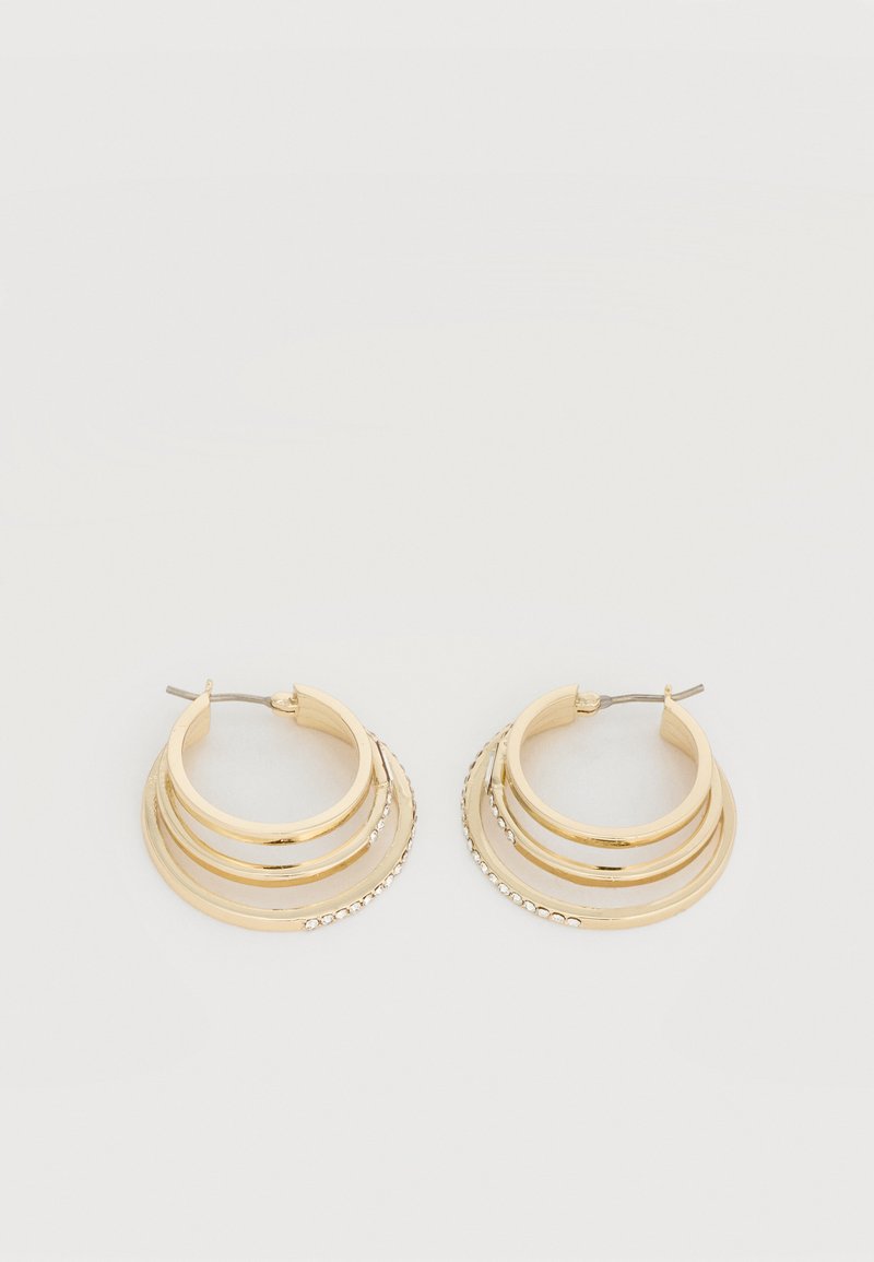 Σκουλαρίκια τριπλού κύκλου σε χρυσό τόνο με μικρές διαφανείς στρας στην εξωτερική άκρη, τοποθετημένα επίπεδα σε απλό λευκό φόντο.