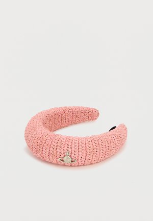 Ružová tkaná čelenka s malým strieborným emblémom v tvare gule pripevneným na prednej strane na jednofarebnom bielom pozadí.