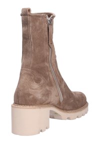 Bota de tobillo de ante topo con suela blanca gruesa, cremallera lateral y mínimos detalles de costura. Presenta un acabado texturizado y forma redondeada.