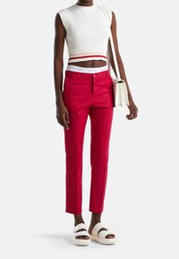 Röda skräddarsydda byxor med slim fit, med dragkedja och sidofickor. Kombinerat med en randig vit crop top och vita sandaler.