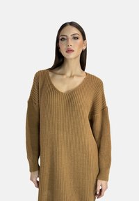 Knit V-neck sweater in warm brown. Oversized fit with drop shoulders and ribbed cuffs. Textured fabric with a loose, cozy appearance.