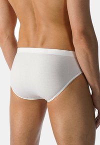 Weiße Baumwollunterhosen mit glatter Textur, elastischem Bund und enger Passform, von hinten gezeigt mit Fokus auf den Beinen und dem Taillenbereich.