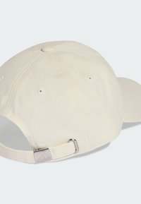 Gorra de béisbol crema con visera curva, hecha de tela. Presenta un ajustador deslizante con un acento metálico en la parte posterior.