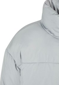 Lysegrå pufferjakke med høy krage, glatt tekstur og quiltet design; har sydd detaljer langs skuldrene.