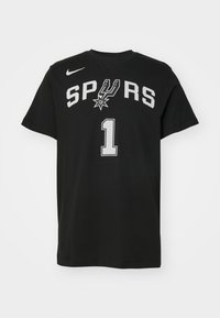 Schwarzes Baumwoll-T-Shirt mit kurzen Ärmeln; zeigt "SPURS" in weißem Text und eine weiße "1" mit einer Mesh-Struktur, sowie ein Nike-Logo oben links.