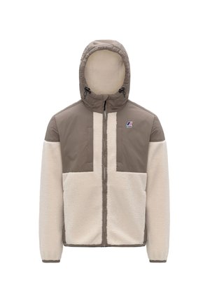 Giacca foderata in pile con una combinazione di colori beige e crema. Presenta un cappuccio, chiusura a zip e un design con pannelli distintivi. Include un dettaglio del logo.
